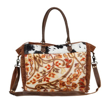 Load image into Gallery viewer, This bag exhibits floral charm and spreads the positive vibes wherever you go. A patch of hairon leather on top breaks the monotony at any given point in time.
