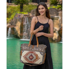 Load image into Gallery viewer, Upcycled from a unique rug, the amber color on the bag stands out against the lighter hues. This spacious messenger bag comes with a strong zippered front and a detachable leather strap. (6537517400262)
